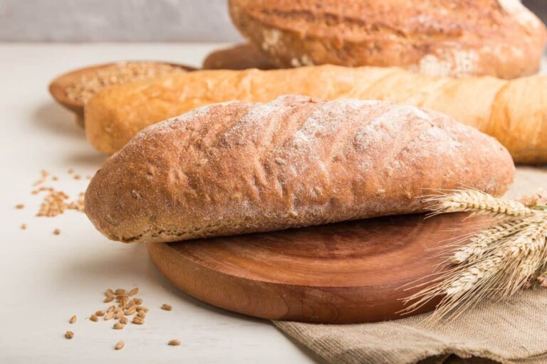 Fresh bread loaves on a round wooden cutting board