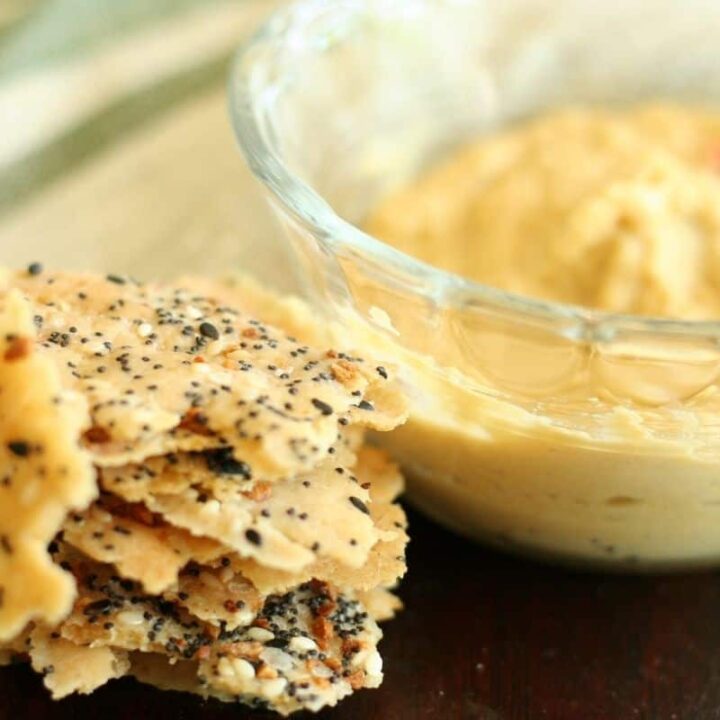 Sourdough Discard Crackers stacked next to a glass bowl filled with hummus