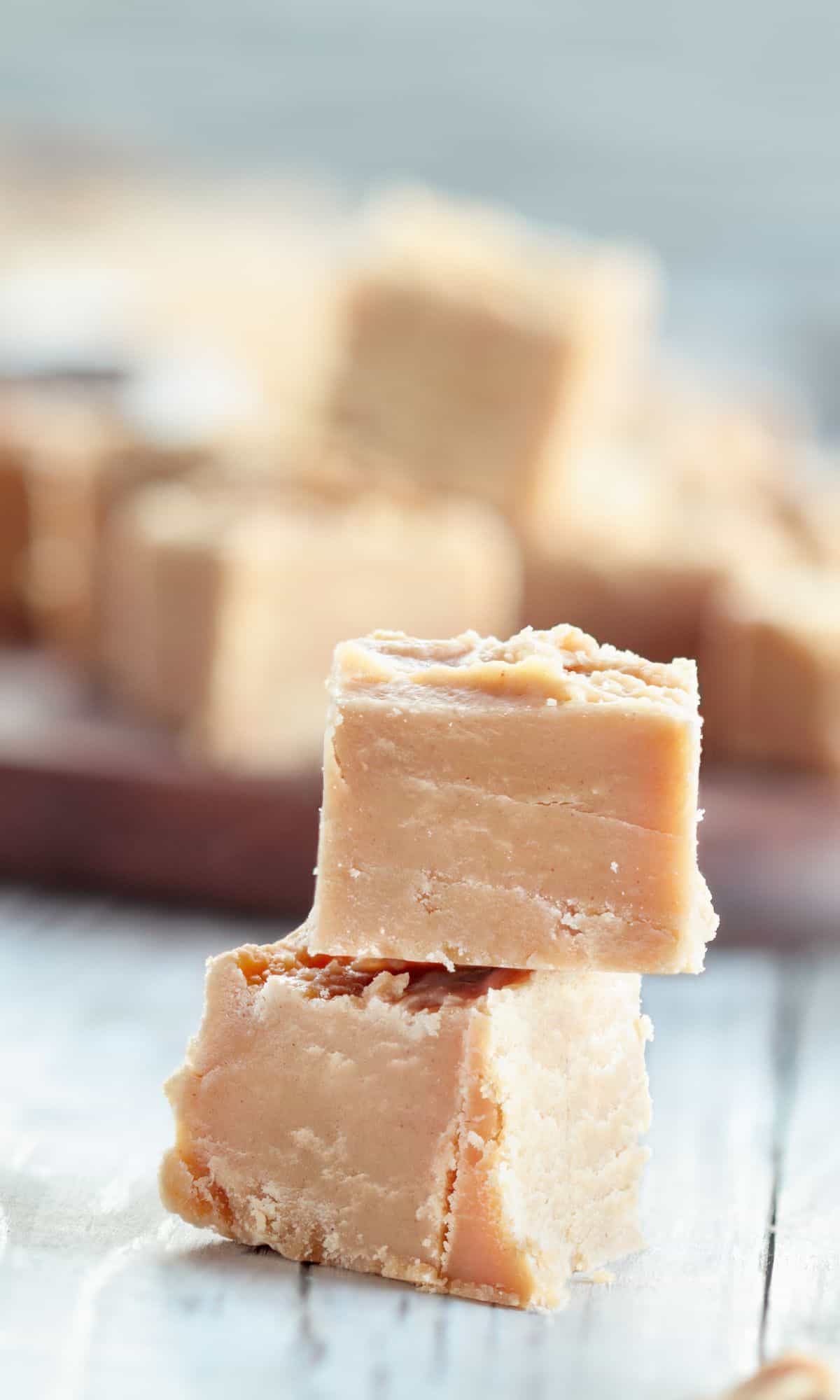 Stacks of cubed homemade peanut butter fudge with chocolate fudge in the background